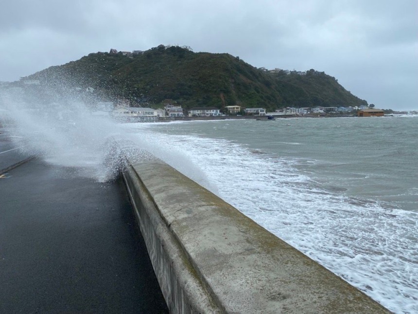 waves are overtopping a seawall in wellington and water is covering the footpath